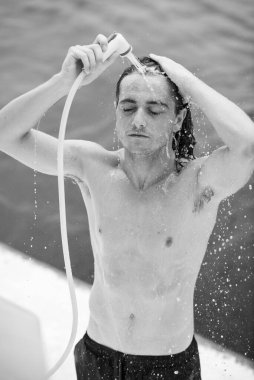 Arka planda duş alan ve okyanus gören siyah ve beyaz sörfçü portresi