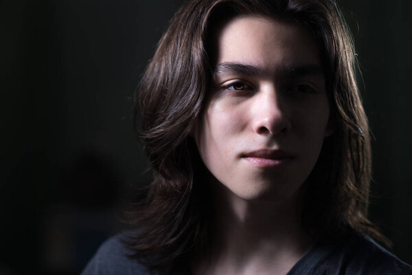 Portrait of young man with long hair in low key with Rembrandt lightning