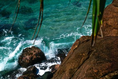 Yukarıdan kahverengi büyük kaya ve mavi okyanus renklerine tropikal adada bakın.