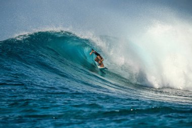 Beyaz dişleri olan yakışıklı bir adamın portresi gülümsüyor, mavi gözler, sörfçü ve mavi okyanus.