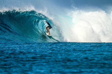 Beyaz dişleri olan yakışıklı bir adamın portresi gülümsüyor, mavi gözler, sörfçü ve mavi okyanus.