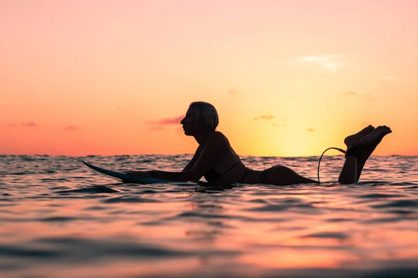 バリのカラフルな夕日の時間に海のサーフボード上の美しい体を持つサーファーの女の子の水からの肖像画 — ストック写真