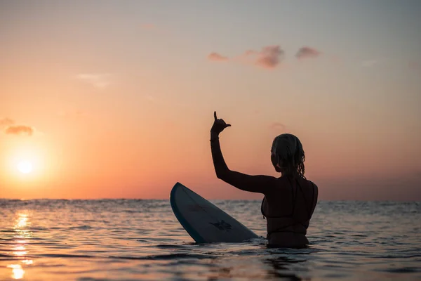 バリのカラフルな夕日の時間に海のサーフボード上の美しい体を持つサーファーの女の子の水からの肖像画 — ストック写真