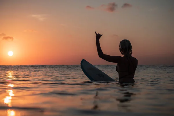 バリのカラフルな夕日の時間に海のサーフボード上の美しい体を持つサーファーの女の子の水からの肖像画 — ストック写真