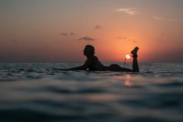 バリのカラフルな夕日の時間に海のサーフボード上の美しい体を持つサーファーの女の子の水からの肖像画 — ストック写真