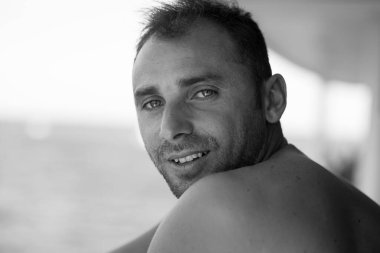 Arka planda sörf tahtası taşıyan yakışıklı bir adamın portresi.