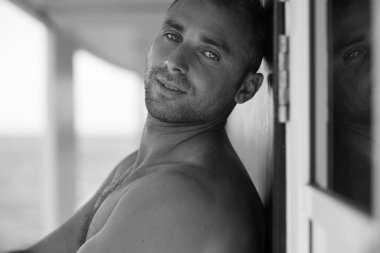 Arka planda sörf tahtası taşıyan yakışıklı bir adamın portresi.