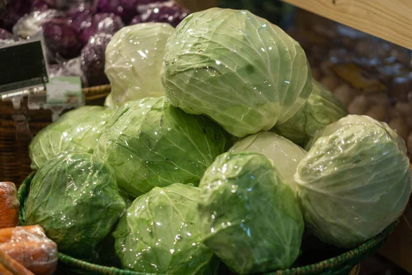 Basket with cabbage heads wrapped in plastic in supermarket