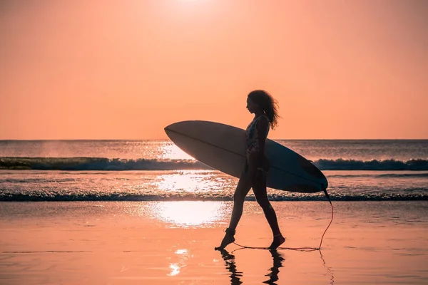 バリのカラフルな夕日でサーフボードとビーチで美しい体を持つ女性サーファーの肖像画 — ストック写真