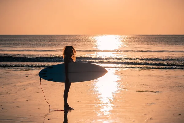 バリのカラフルな夕日でサーフボードとビーチで美しい体を持つ女性サーファーの肖像画 — ストック写真