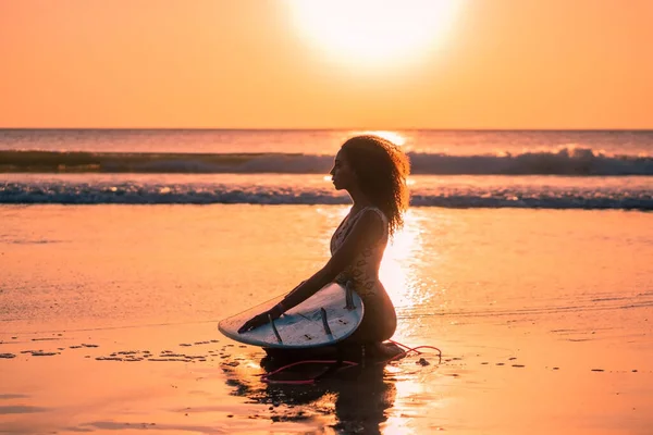 バリのカラフルな夕日でサーフボードとビーチで美しい体を持つ女性サーファーの肖像画 — ストック写真