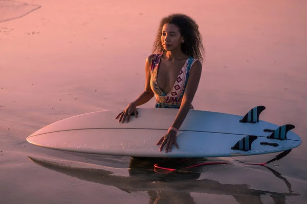 バリのカラフルな夕日でサーフボードとビーチで美しい体を持つ女性サーファーの肖像画 — ストック写真