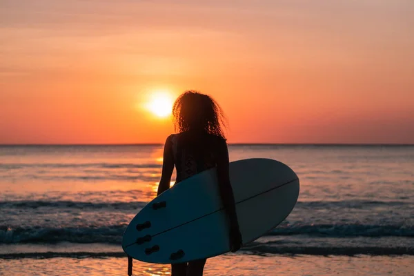 バリのカラフルな夕日でサーフボードとビーチで美しい体を持つ女性サーファーの肖像画 — ストック写真