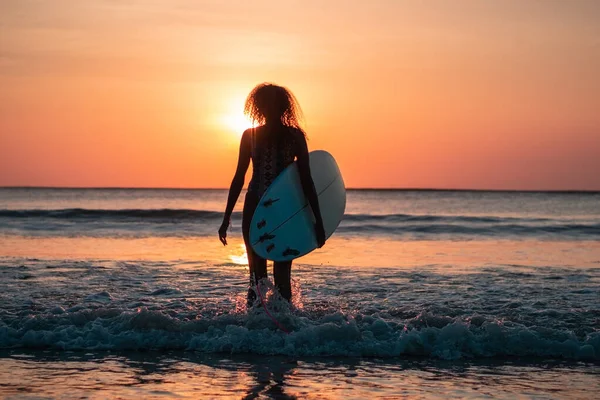 バリのカラフルな夕日でサーフボードとビーチで美しい体を持つ女性サーファーの肖像画 — ストック写真