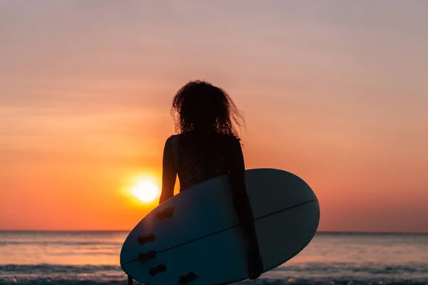 バリのカラフルな夕日でサーフボードとビーチで美しい体を持つ女性サーファーの肖像画 — ストック写真