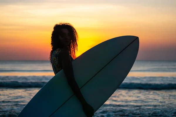 バリのカラフルな夕日でサーフボードとビーチで美しい体を持つ女性サーファーの肖像画 — ストック写真