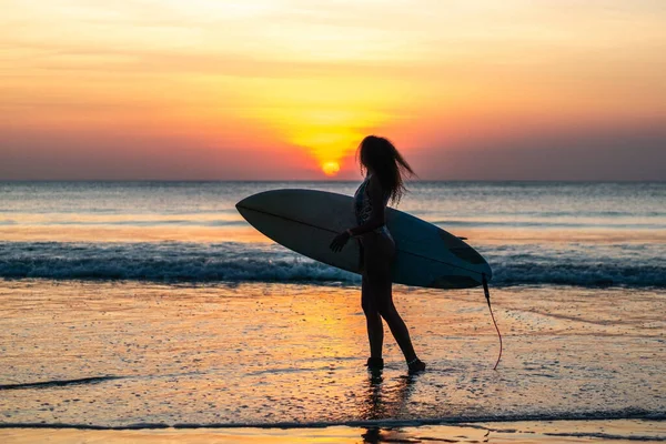 バリのカラフルな夕日でサーフボードとビーチで美しい体を持つ女性サーファーの肖像画 — ストック写真