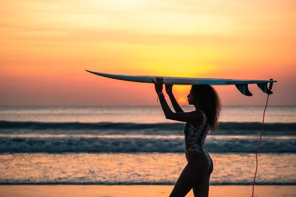 バリのカラフルな夕日でサーフボードとビーチで美しい体を持つ女性サーファーの肖像画 — ストック写真