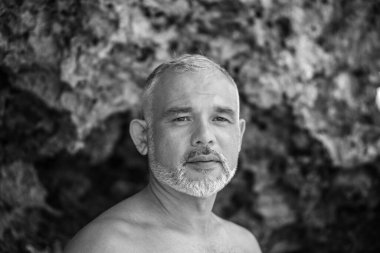 Bali 'de beyaz sörf tahtası ve kaktüs tutan yakışıklı bir sörfçünün siyah beyaz portresi.