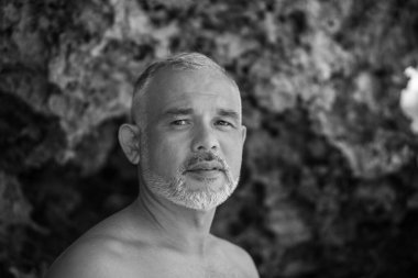 Beyaz sörf tahtası ve Bali arka planında yeşil kaktüs tutan yakışıklı sörfçü portresi.