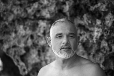Bali 'de beyaz sörf tahtası ve kaktüs tutan yakışıklı bir sörfçünün siyah beyaz portresi.