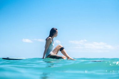 Mavi okyanusta sörf tahtasındaki sörfçü kızın portresi Bali 'deki sudan çekilmiştir.