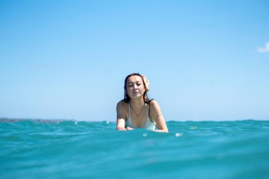 Mavi okyanusta sörf tahtasındaki sörfçü kızın portresi Bali 'deki sudan çekilmiştir.