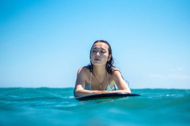 Mavi okyanusta sörf tahtasındaki sörfçü kızın portresi Bali 'deki sudan çekilmiştir.