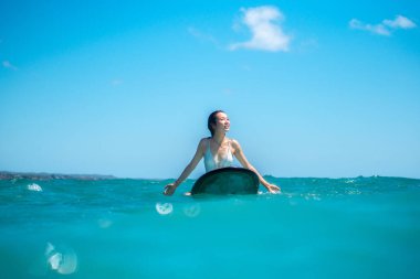 Mavi okyanusta sörf tahtasındaki sörfçü kızın portresi Bali 'deki sudan çekilmiştir.