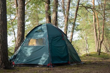 Göl kenarındaki güzel bir ormanda kamp alanında büyük bir turist çadırı kurulur. Çadırla kamp yapmak. COVID-19 karantinası sırasında ormanda kendini izole etmiş..