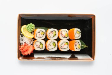 Beyaz bir tabakta dikdörtgen seramik tabakta Japon mezeleri bulunan bir porsiyon maki suşisi. Üst görünüm.