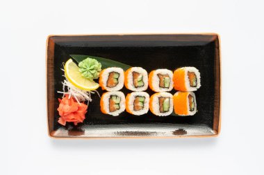Beyaz bir tabakta dikdörtgen seramik tabakta Japon mezeleri bulunan bir porsiyon maki suşisi. Üst görünüm.