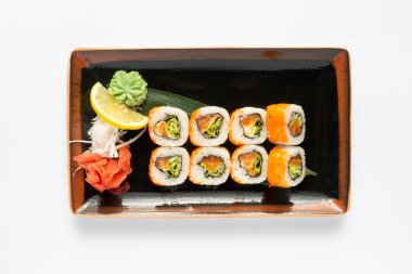 Beyaz bir tabakta dikdörtgen seramik tabakta Japon mezeleri bulunan bir porsiyon maki suşisi. Üst görünüm.