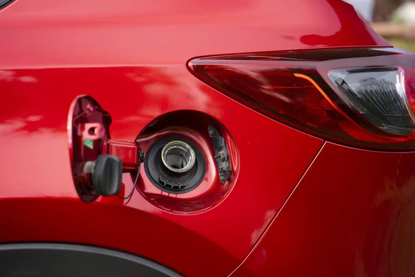 Benzin ya da mazot doldurmak için kırmızı bir arabanın açık yakıt deposu kapağı. Arabanın arkasında açık bir benzin deposu var..
