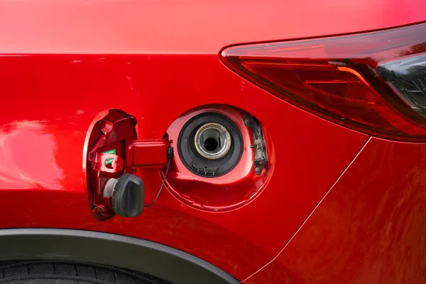 Benzin ya da mazot doldurmak için kırmızı bir arabanın açık yakıt deposu kapağı. Arabanın arkasında açık bir benzin deposu var..