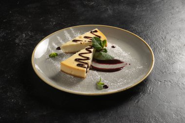 Klasik tatlı. İki dilim çilek soslu cheesecake. Nane yaprağı ve pudra şekerle süslenmiş..