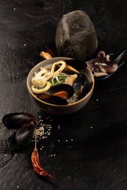 Midye, ahtapot, kalamar halkası, erişte, susam tohumu ve kurutulmuş kırmızı biberli Asya deniz ürünleri çorbası.