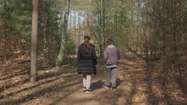 Bir anne ve oğlu sonbahar ormanlarında manzaralı bir patikada birlikte yürüyorlar. Aile doğa yürüyüşünü seviyor, eğlence ve sağlıklı bir yaşam tarzı için doğada kaliteli zaman geçiriyor..