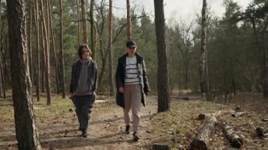 Bir kadın ve oğlu ormanda dikkatli bir yürüyüşün tadını çıkarıyorlar, ağaçları ve doğayı gözlemliyorlar. Aile, zihinsel sağlık ve rahatlama için orman banyosu (shinrin-yoku) yapıyor..