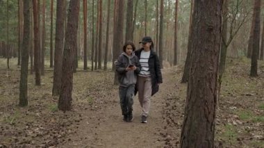 Ergen çocuk ve anne yürüyüş yaparken birlikte bir telefon ekranına bakarlar. Seyrüsefer için mobil uygulama kullanan bir aile ya da online eğlence şirketi. Modern ebeveynlik ve dijital teknoloji.