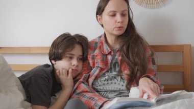 Anne çocuğuna yüksek sesle okuyor, onun okuma yazma becerilerini geliştirmesine yardım ediyor. Ebeveyn ve oğul, akıcı ve doğru telaffuz edilen bir kitaptaki metni birlikte takip ederler..