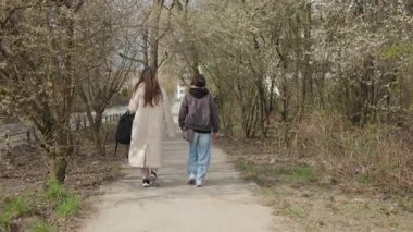 Bir anne ve oğlu, bir bahar parkından eve dönerken kameradan uzaklaşıyorlar. Bir ebeveyn ve çocuk, çiçek açan ağaçlarla çevrili bir yolda birlikte günlük bir yolculuğa çıkıyorlar. Aile ve doğa.