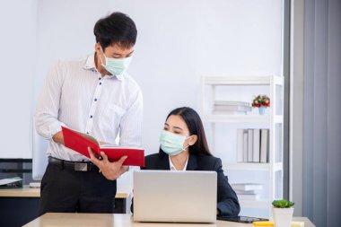 Ofis çalışanı, covid-19 salgınının önlenmesi için cerrahi maske ile çalışmalarını tartışıyor