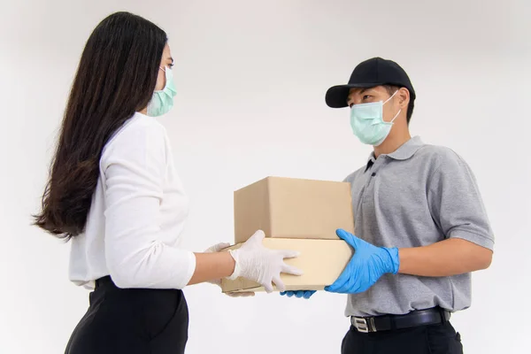 Teslimatçı, cerrahi maske ve eldiven takarak müşteriye paket getiriyor.