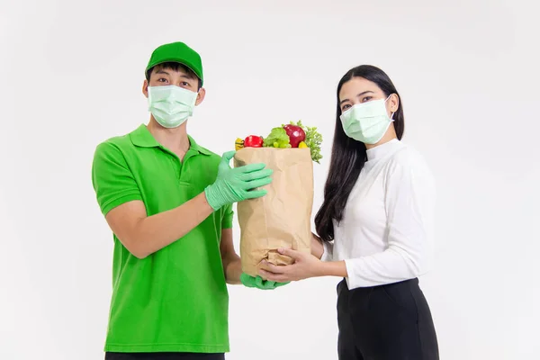Kadın, hem cerrahi maske takan hem de eldiven takan yemek dağıtan adamdan virüs önleyici malzemeler alıyor.