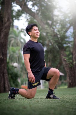 Asyalı genç adam parkta egzersiz yapıyor.