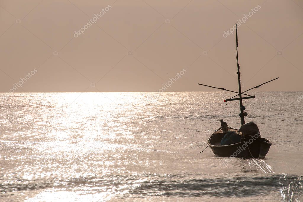 Fishing Boat floating on the sea in themorning goolden sun