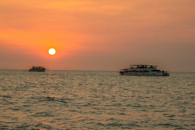 Günbatımında okyanusta yelken açan yat.
