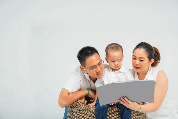 Thai - chinese parent  read book with their son with copyspace