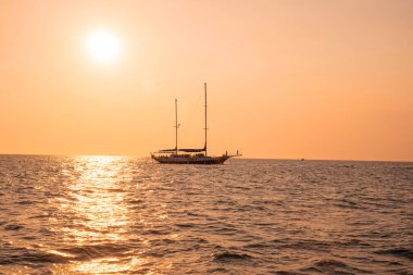 Altın günbatımında okyanusta yüzen yat
